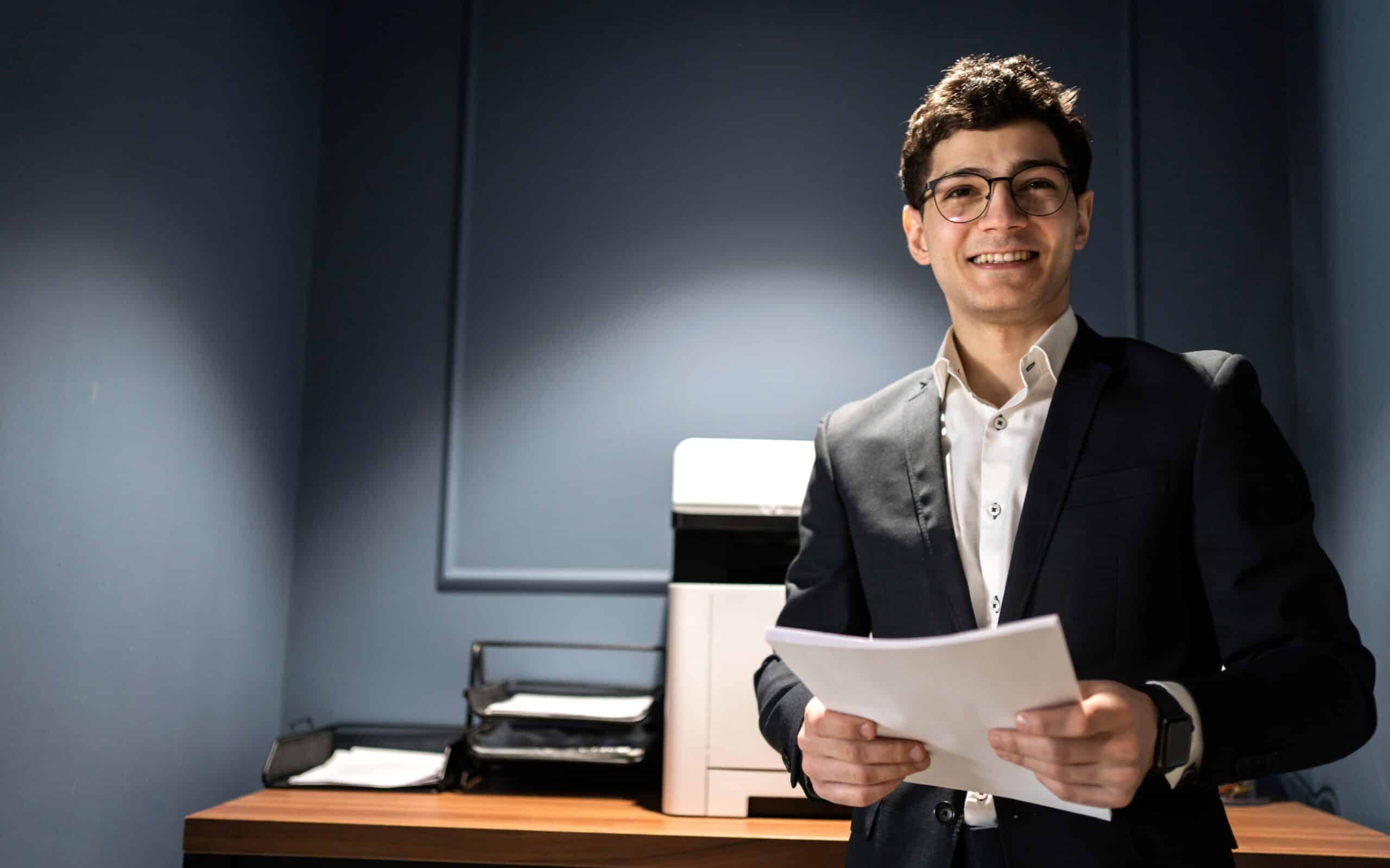 financier in glasses uses a printer in the office, businessman formal wear holds documents